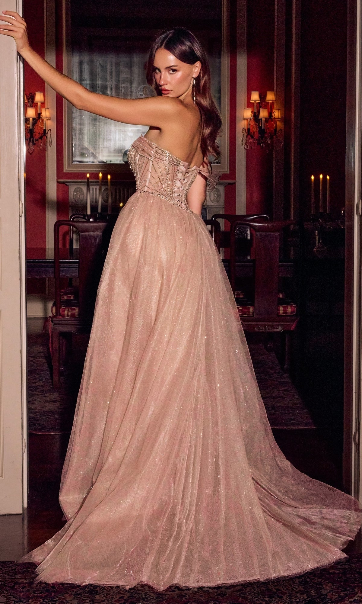 A woman wears the Long Prom Dress: Ladivine CC506, a strapless, floor-length blush gown with a fitted, beaded corset bodice and a full, glitter tulle skirt.